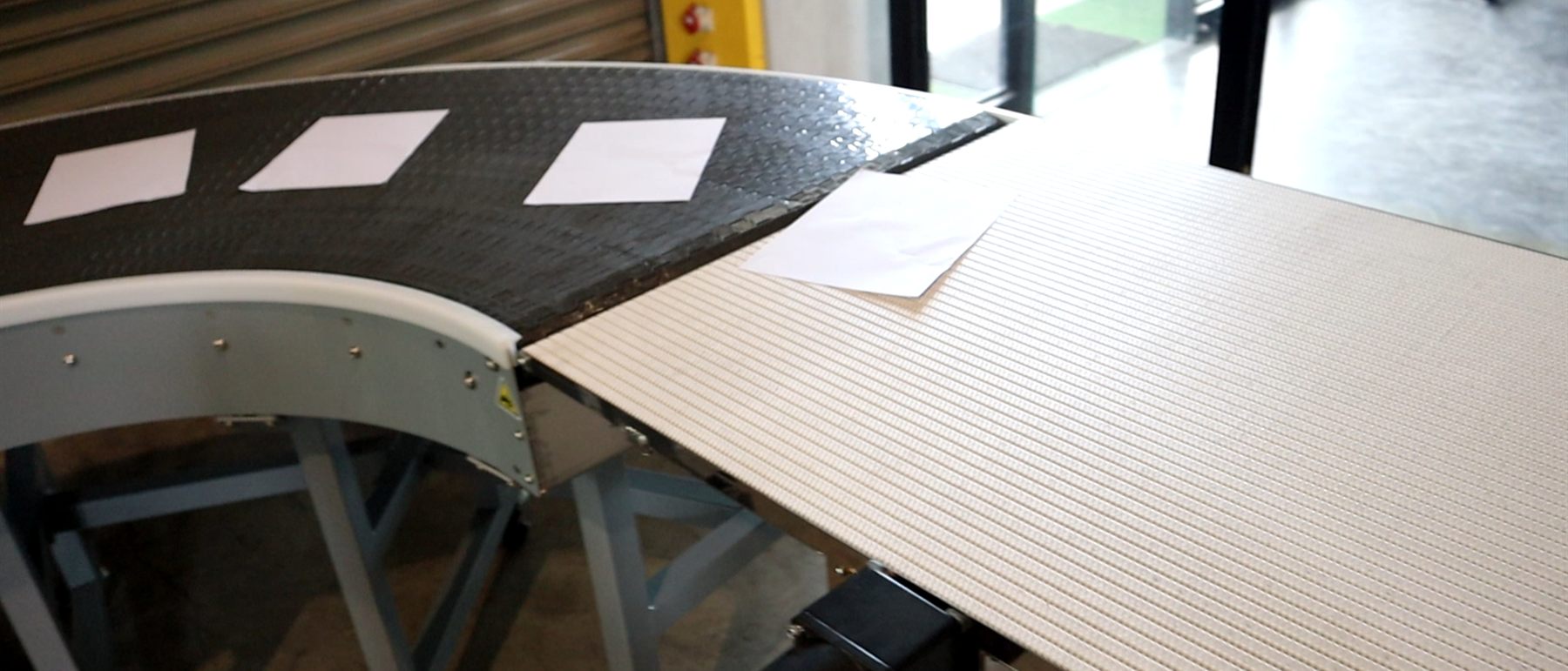 A curve conveyor carrying printed sheets beside a printing machine.