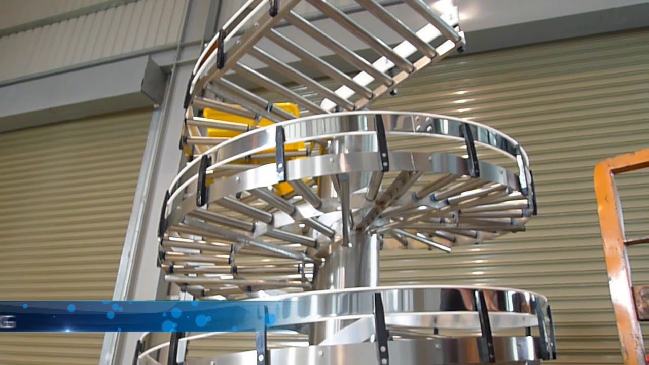 A stainless steel gravity roller spiral conveyor with several rows of rollers on its track.