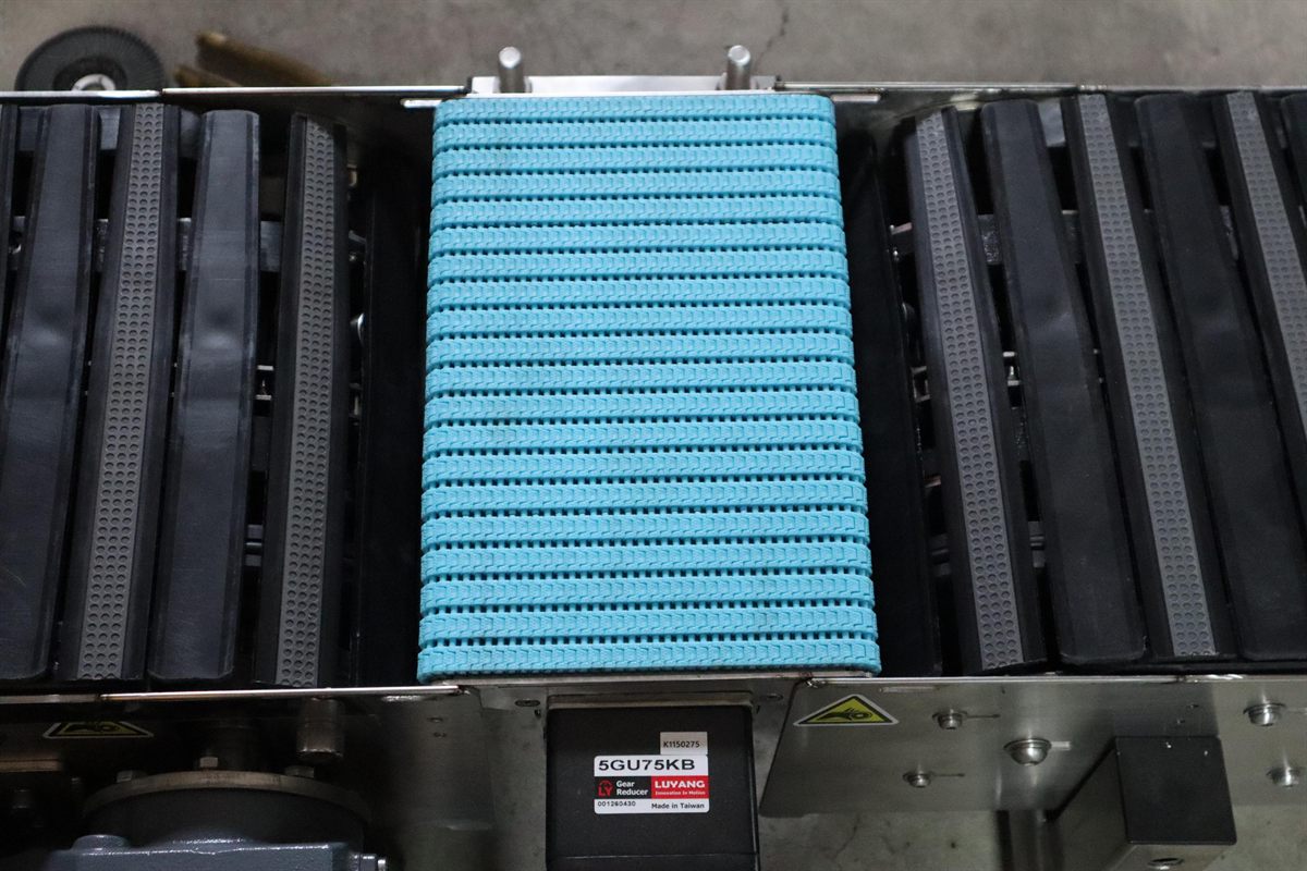 A miniature conveyor connecting two straight conveyor sections.