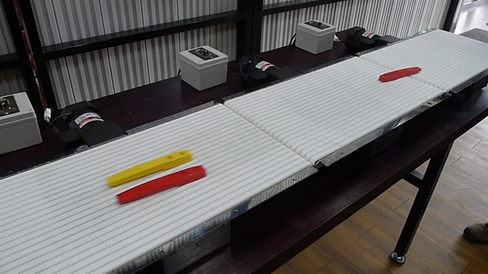 A NEXUS miniature conveyor carrying small items between two machines.