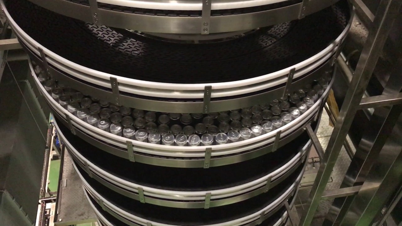 Cans filling the tiers of a spiral conveyor with dark slat chain.