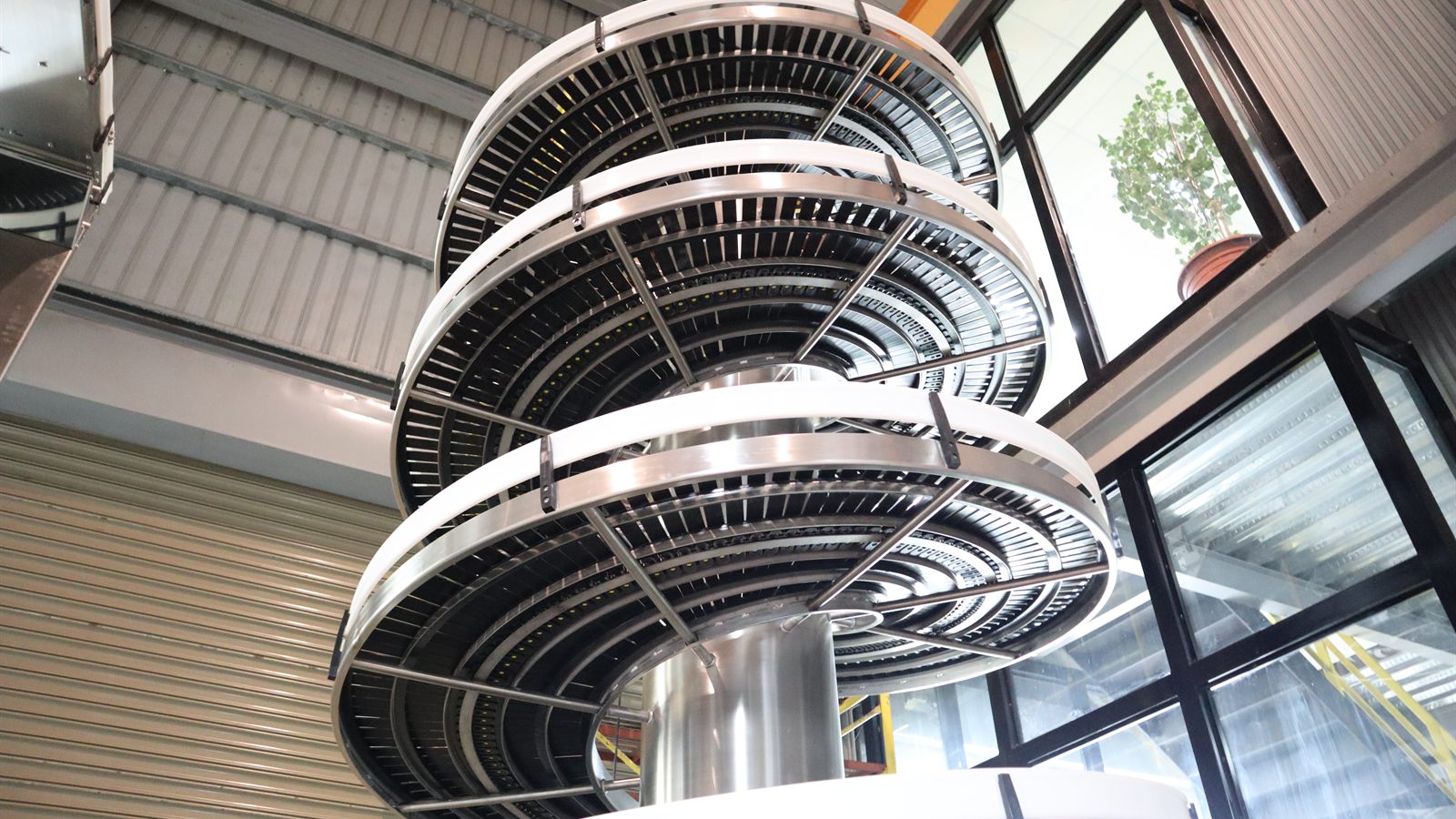 A stainless steel spiral conveyor rising through several turns in the NEXUS factory.
