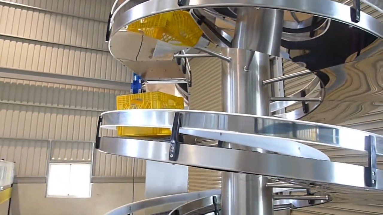 Yellow plastic baskets on a stainless steel spiral conveyor.
