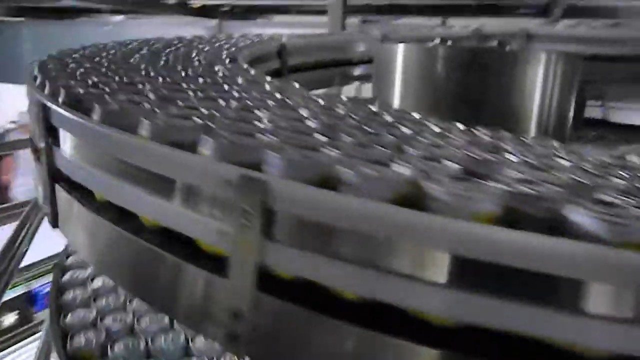 Cans travelling in mass flow on the slat chain of a stainless spiral conveyor.
