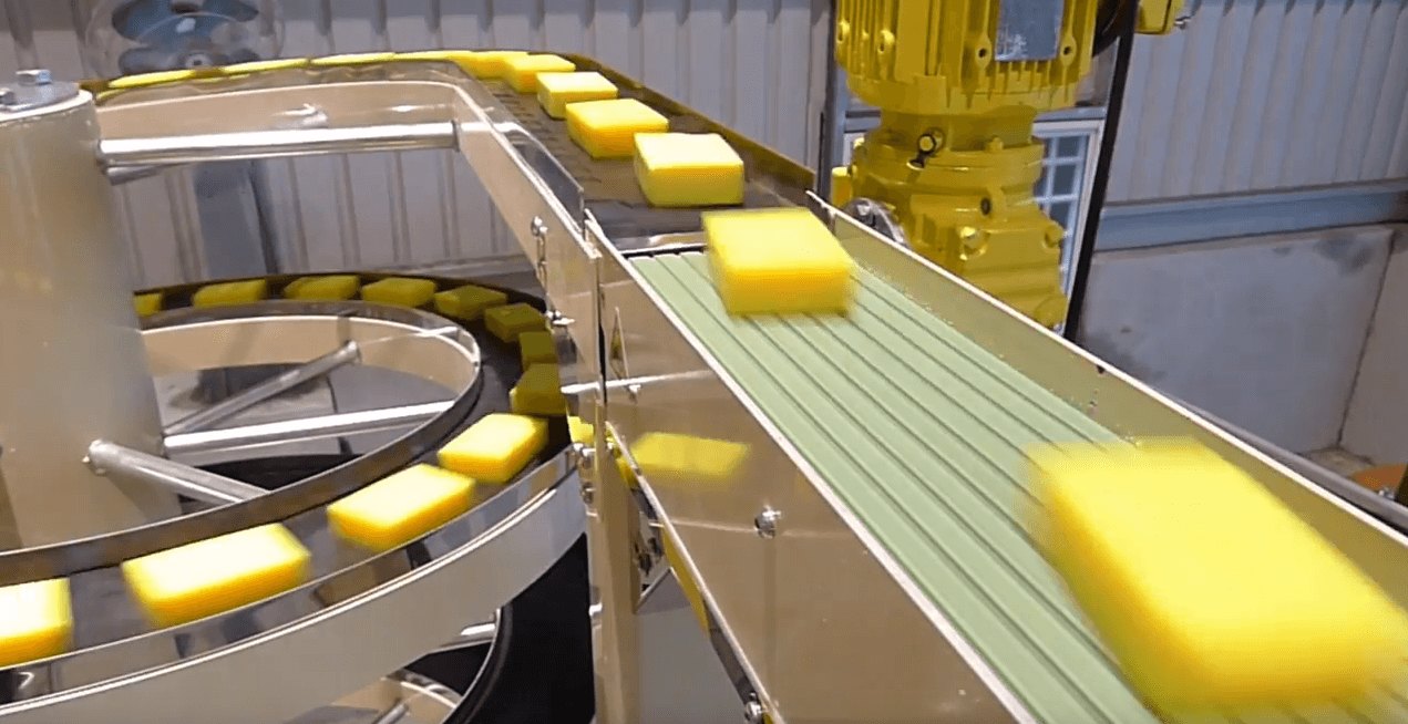 Yellow soap bars spaced along the narrow conveying track of a spiral conveyor during a factory test run.